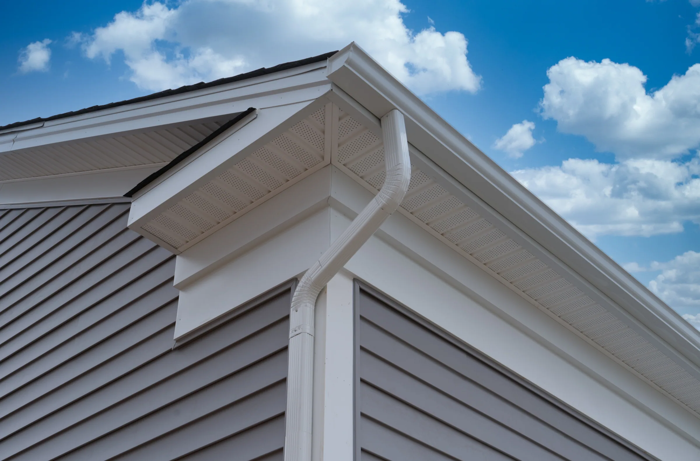 Newly installed white seamless gutter against a Chattanooga blue sky
